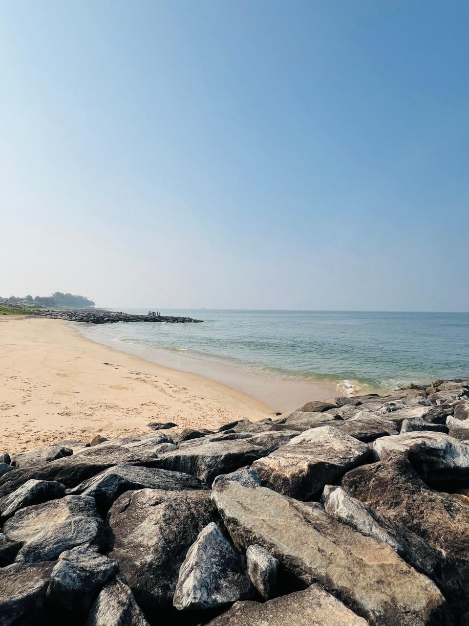 A sandy beach and calm sea viewed from a rocky breakwater