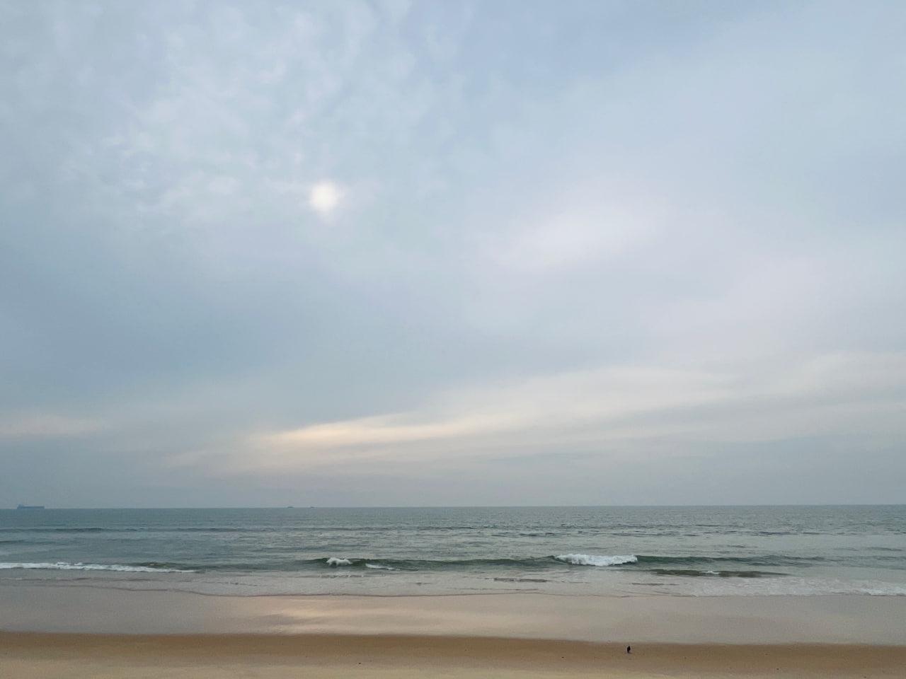 Gentle waves meeting a sandy beach beneath a cloudy sky
